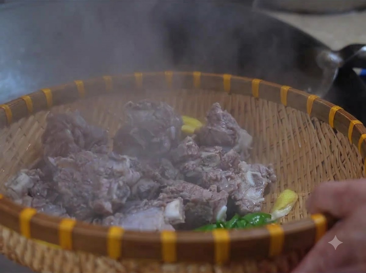 Blanching beef ribs sitting inside a bamboo basket while being rinsed with warm water.