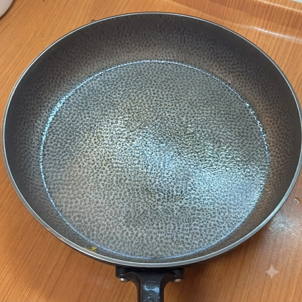 An empty heated frying pan with a textured surface on a kitchen counter.