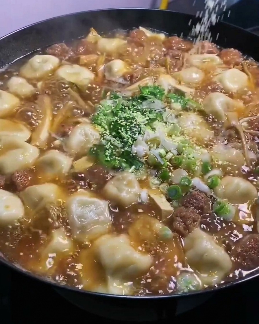 Chicken bouillon powder being sprinkled from above into the bubbling wok.