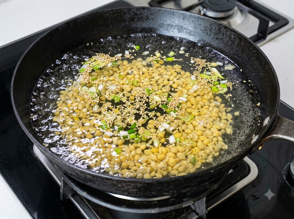 A large amount of yellow soybean sprouts boiling in a wok of water with chopped scallions.