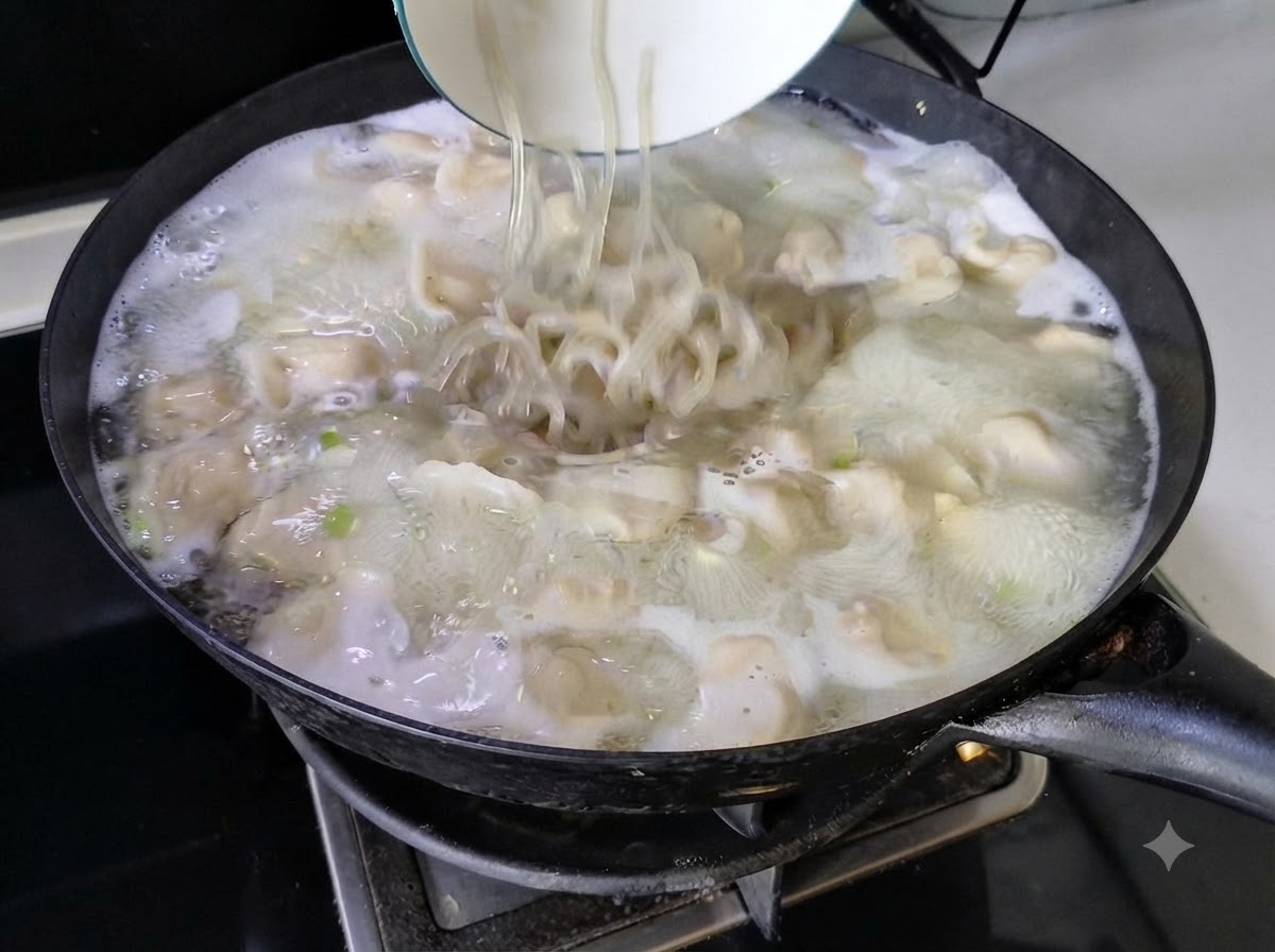 Noodles being poured from a white bowl into the bubbling dumpling soup in a wok.