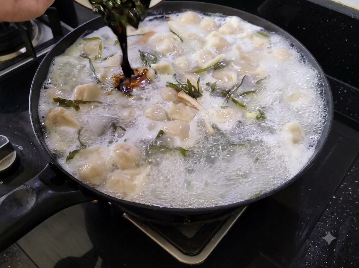 Dark seasoning sauce being poured from a small dish into a large pot of boiling dumpling soup.