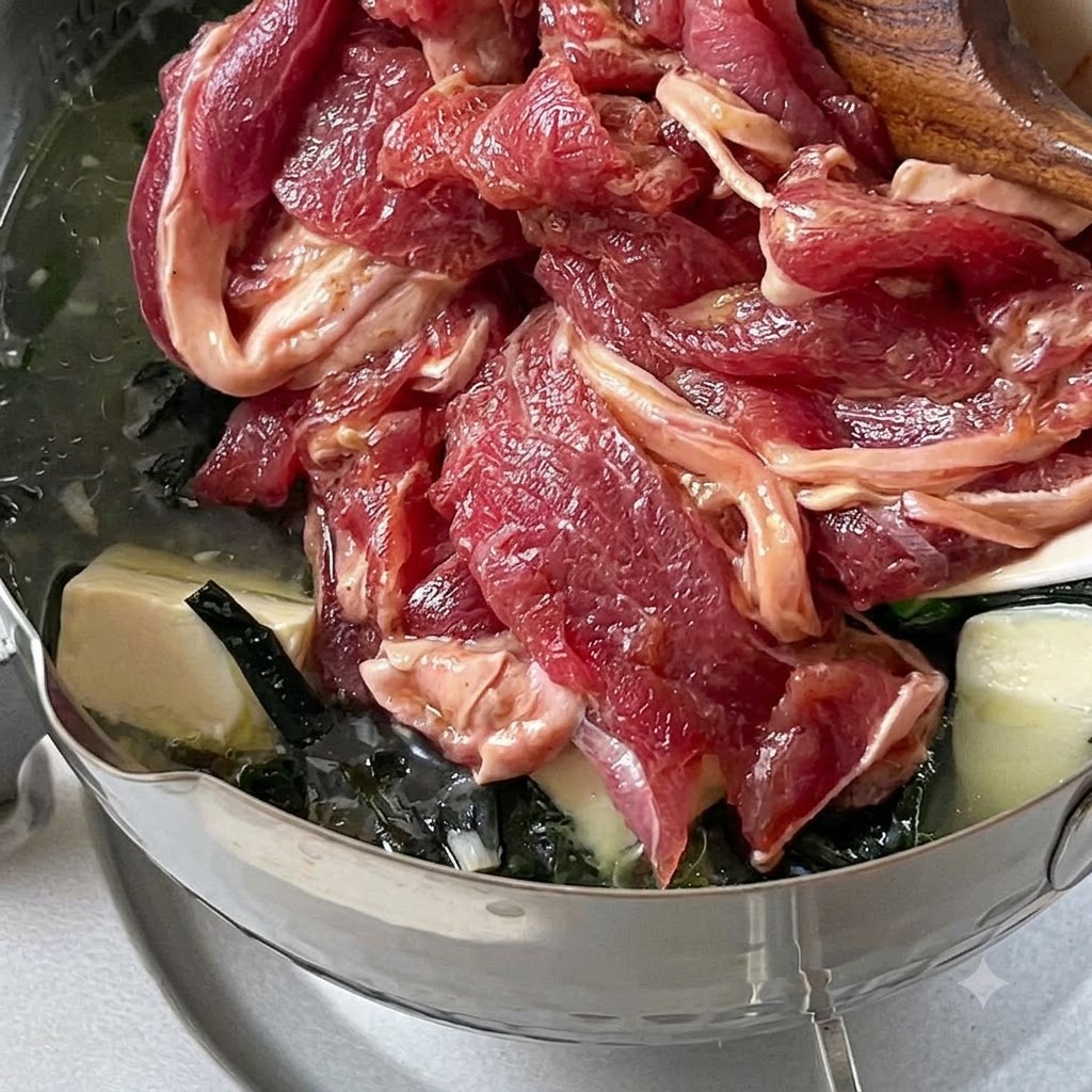 Marinated beef slices being dropped into a pot of simmering soup on low heat.