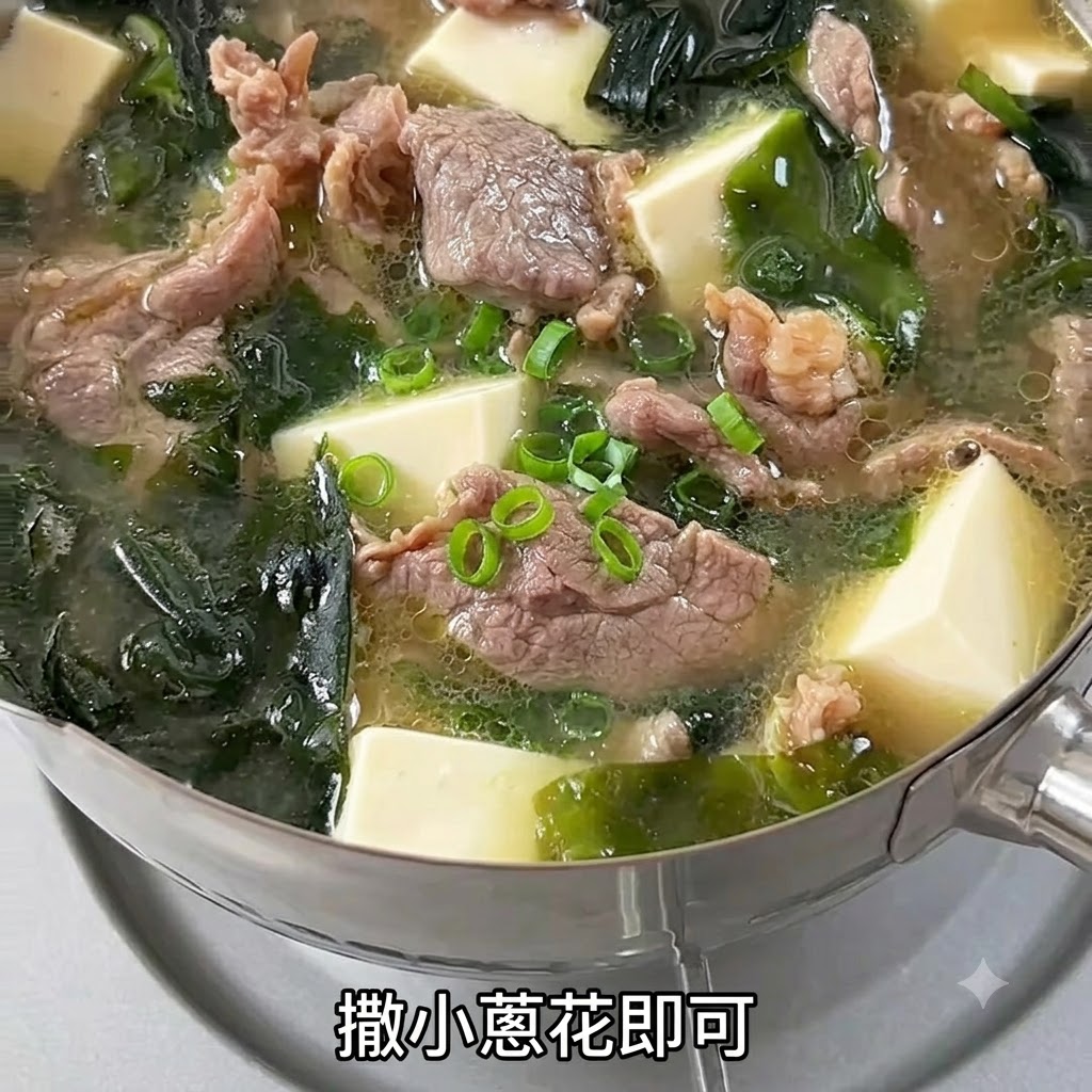 Freshly chopped green onions sprinkled over the top of a steaming bowl of beef and tofu soup.