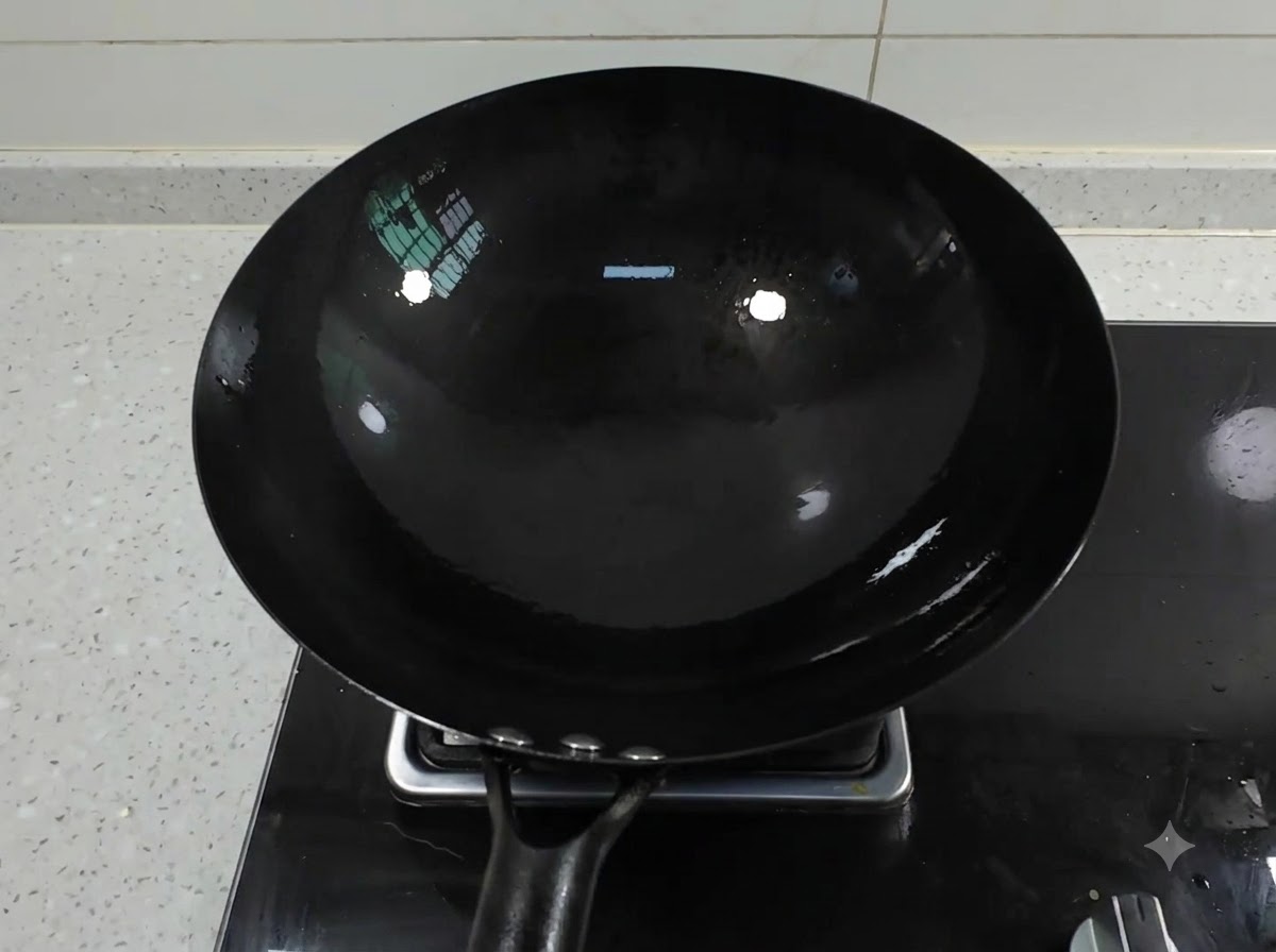 A clean black iron wok sitting on a gas stove burner with oil pooling inside.