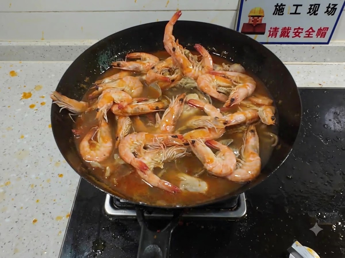 A large lobster being added into a crowded wok filled with simmering seafood and rich red broth.
