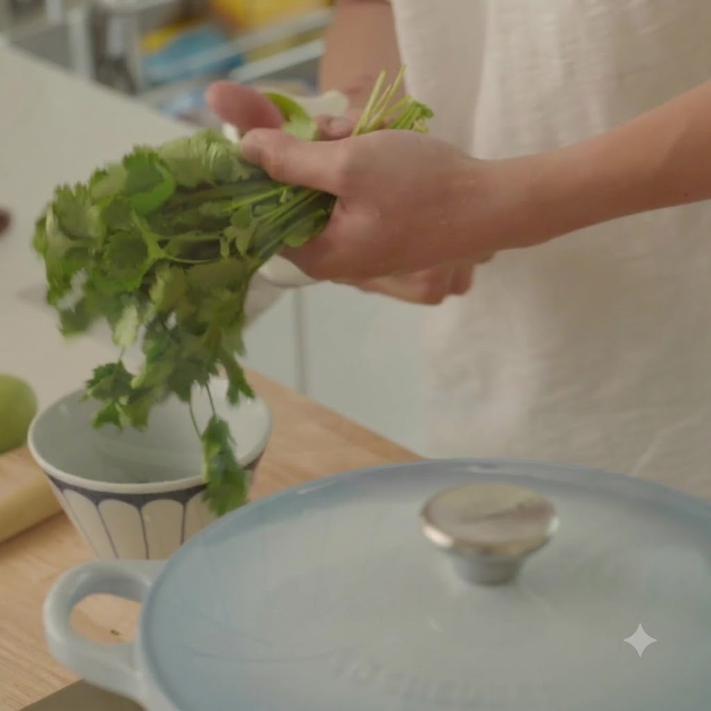 Fresh cilantro being prepared and chopped near a bowl and a cooking pot.