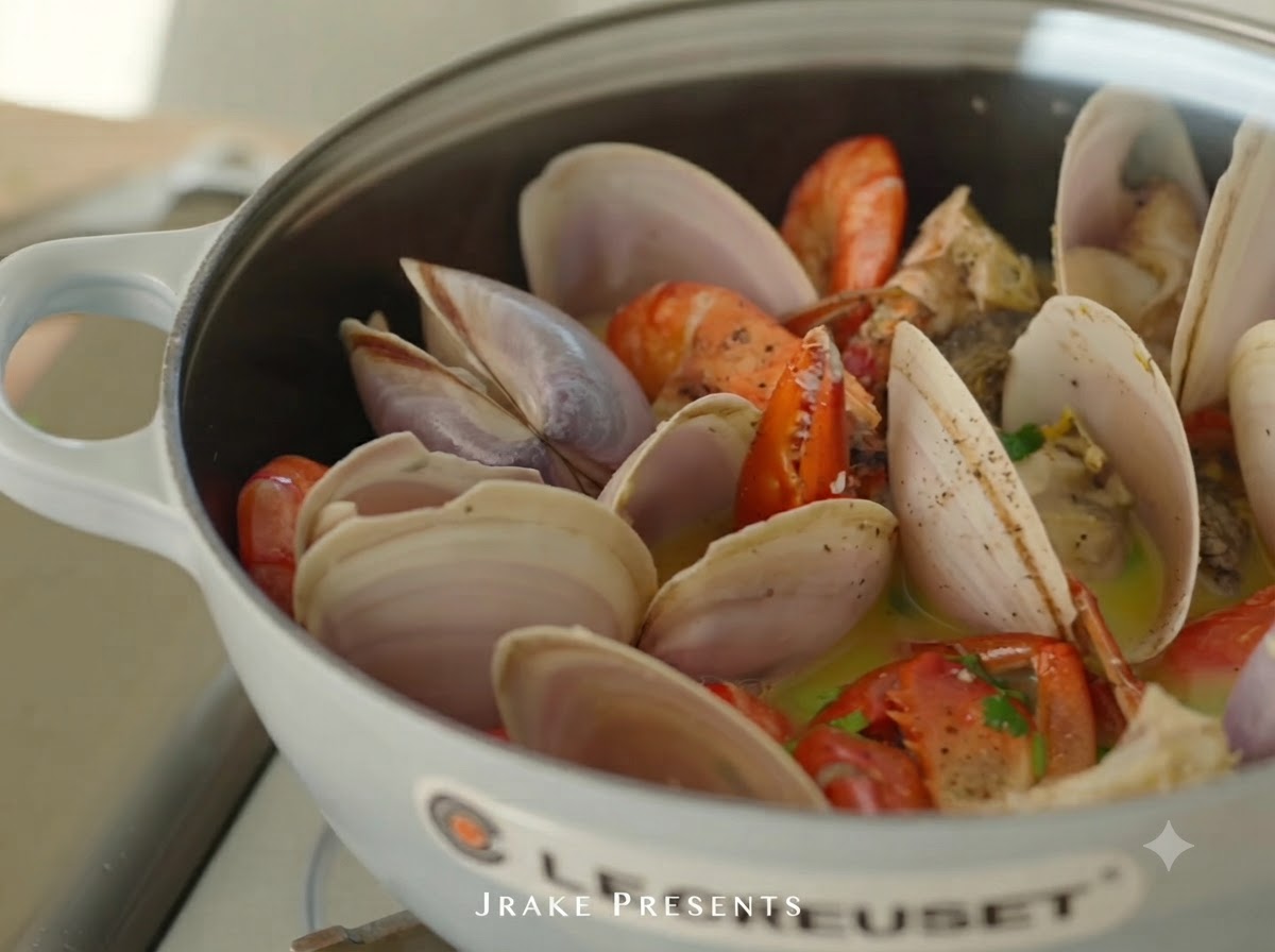 Fresh lemon juice being squeezed over the cooked seafood pot.