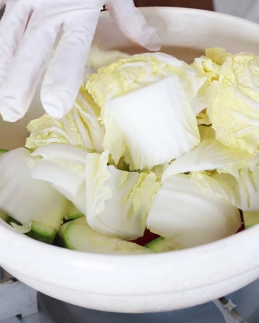 Chunks of baby cabbage being added on top of the vegetables in the pot.