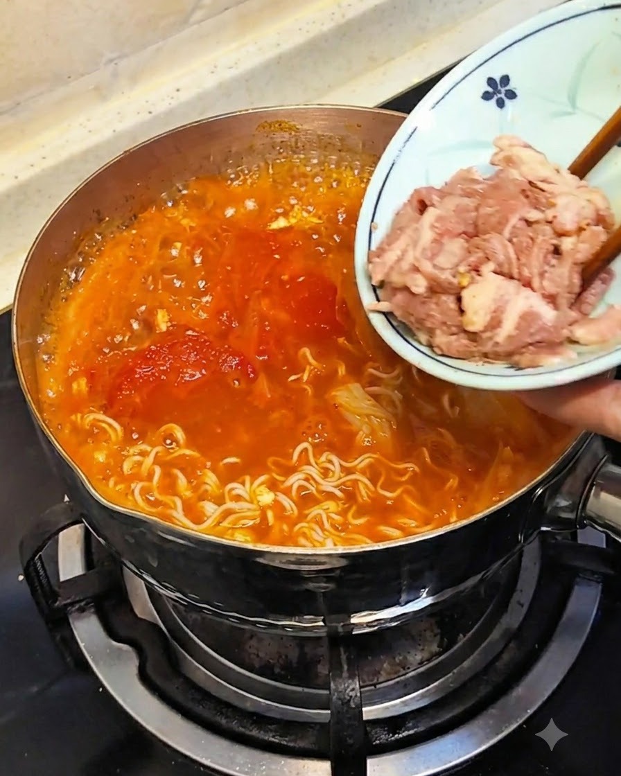 Chopsticks submerging raw, thinly sliced meat from a small plate into the hot broth.