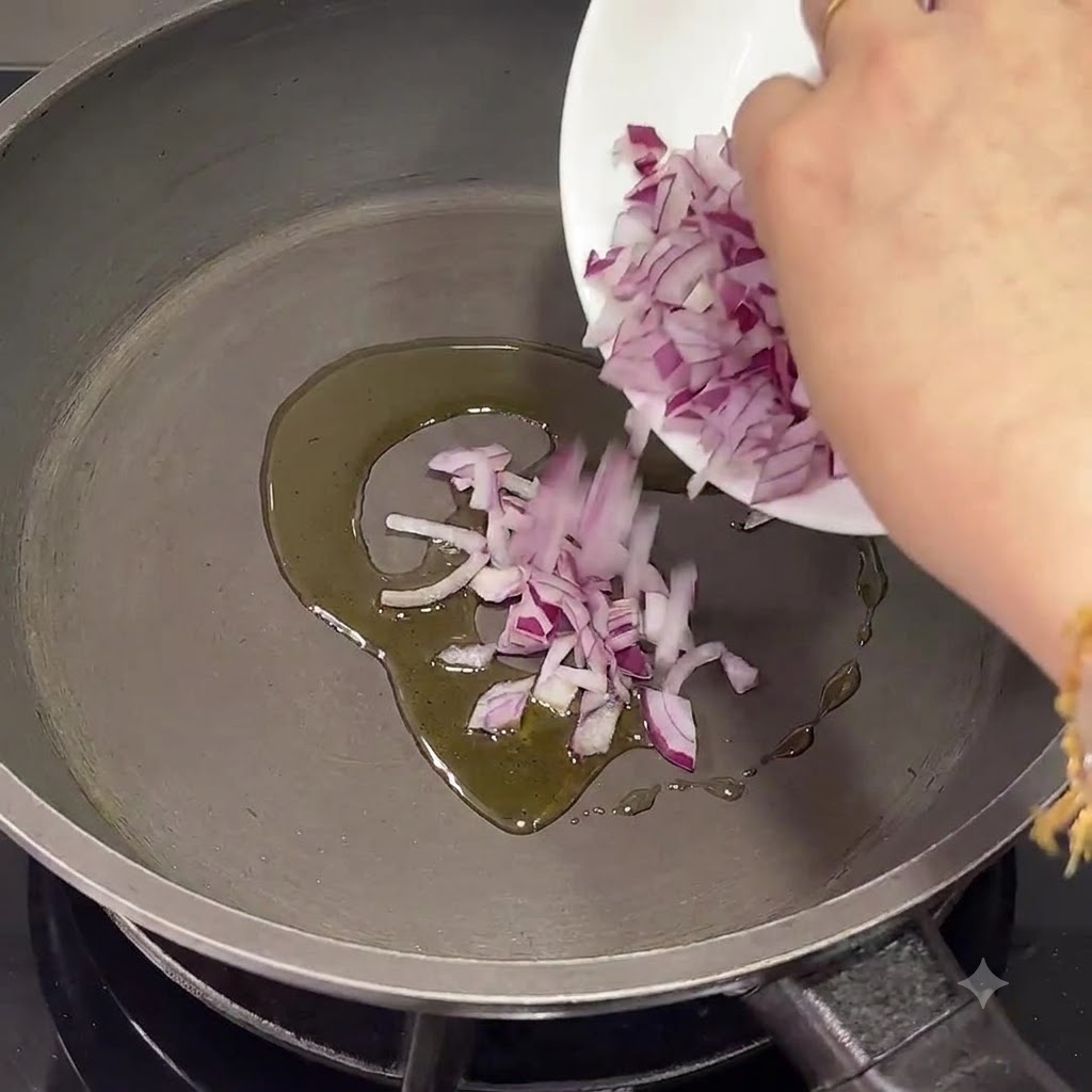 Chopped red onions being poured into a pan with warm olive oil.