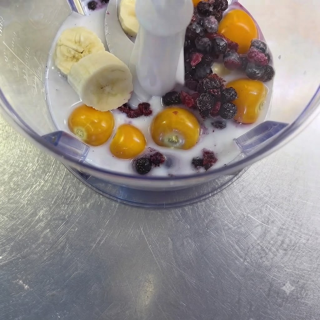 A clove of raw garlic sitting among the fruit and milk mixture inside the blender cup.