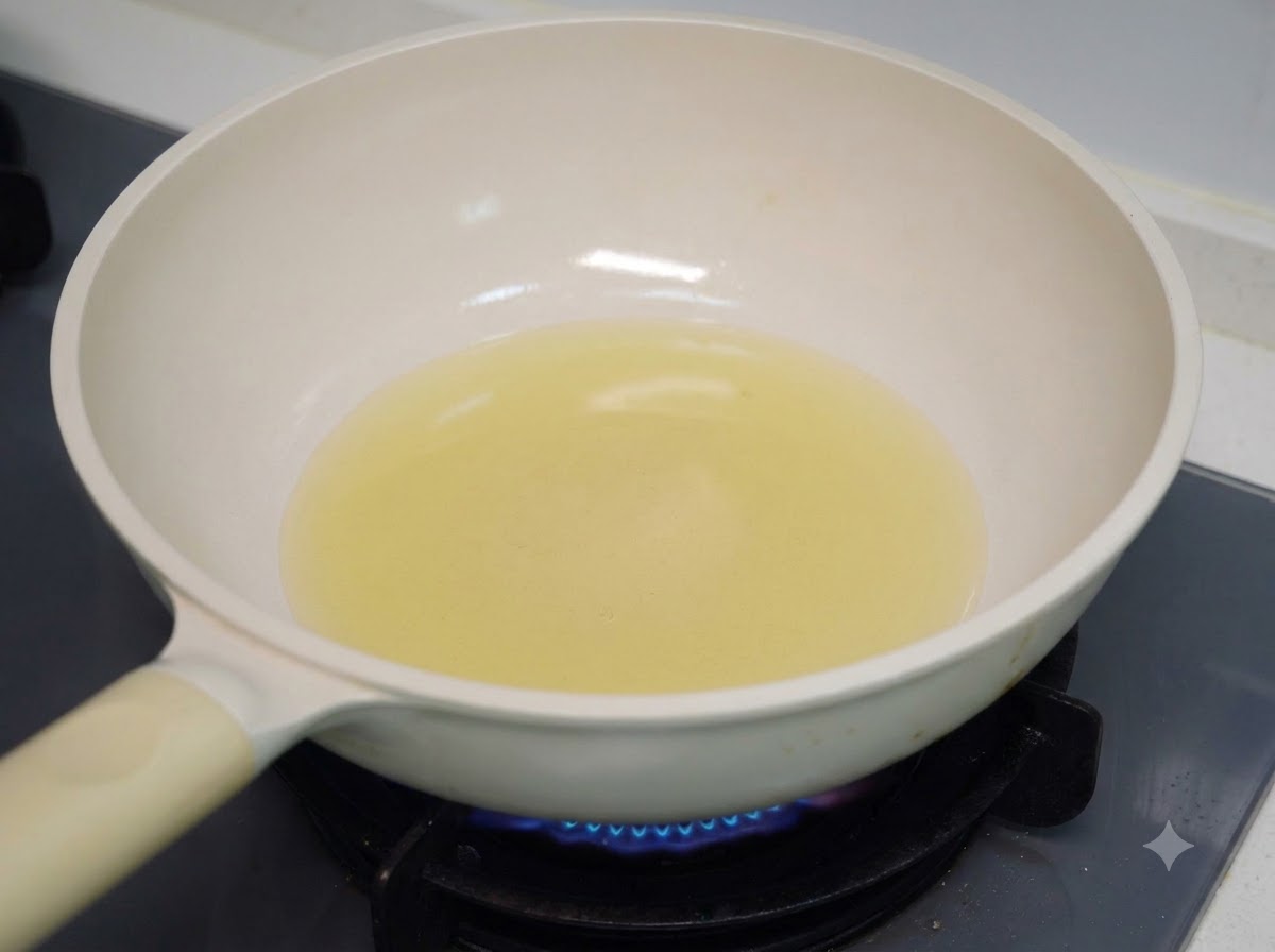 Cooking oil heating in a white pan on a gas stove burner.