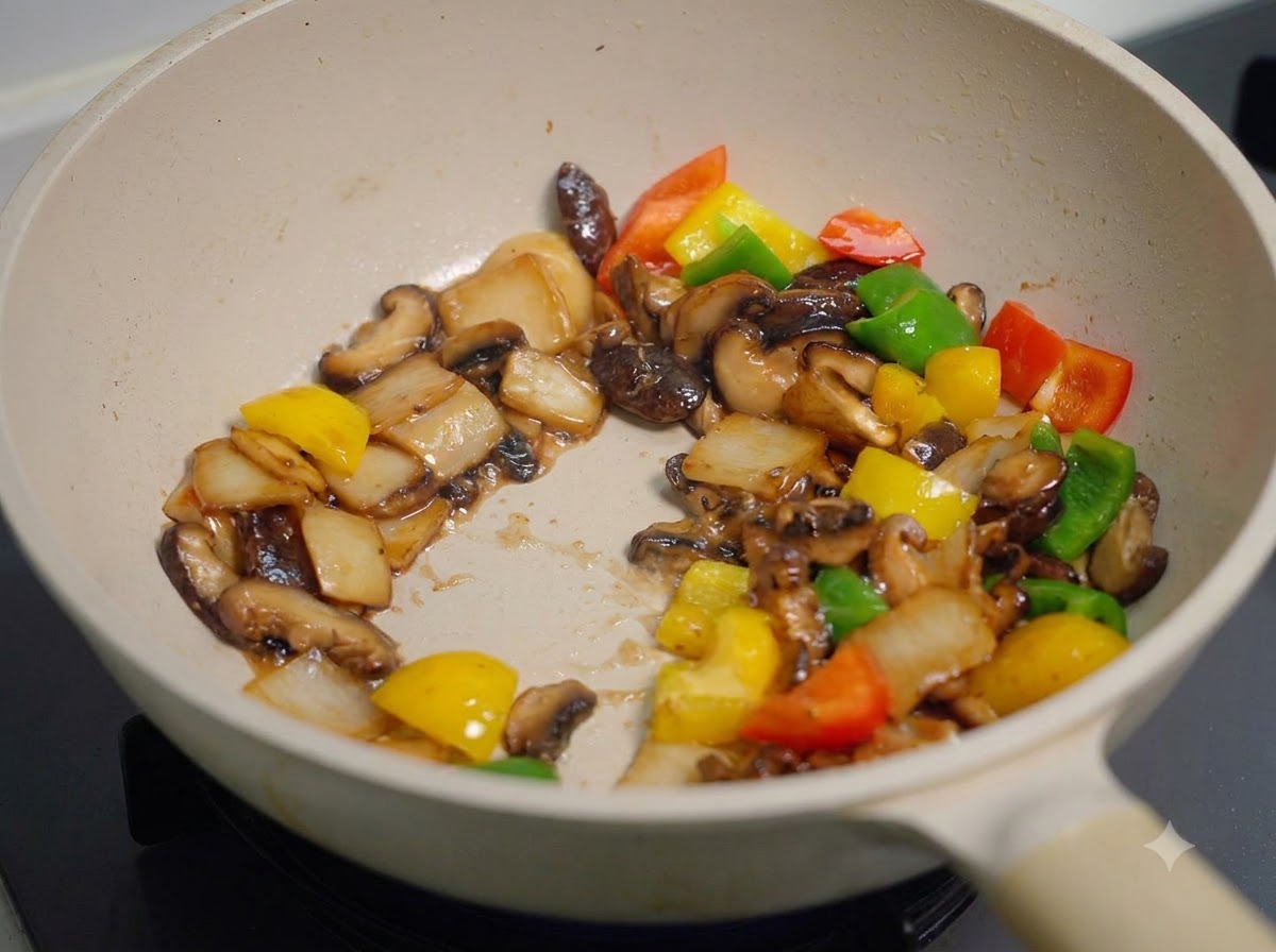 All the mushrooms and bell peppers being stir-fried and tossed rapidly in the pan, evenly coated with a thick dark sauce.