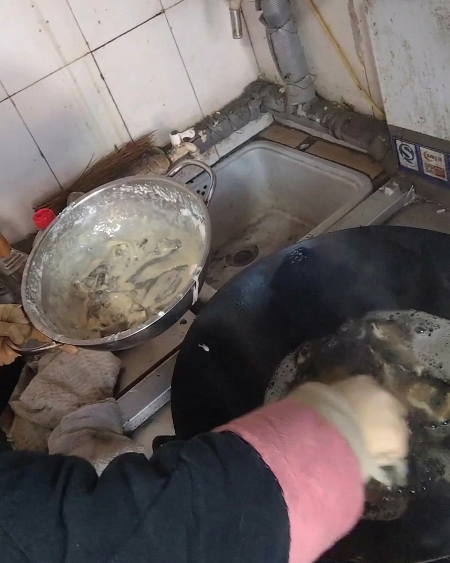 Frying coated mushroom strips in a wok filled with hot oil.