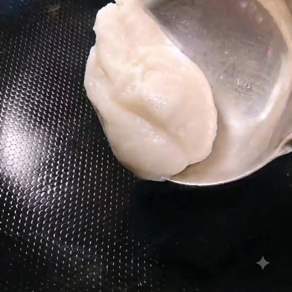 A ladle adding a scoop of white pork lard into a heated black wok.