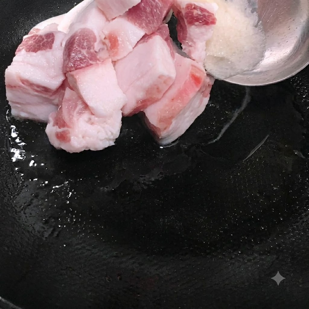 Fatty pork slices being placed into the wok alongside melted lard.