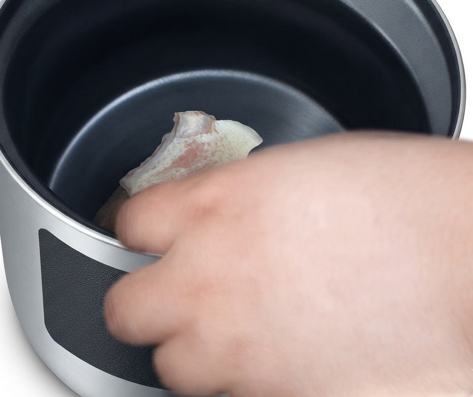 Blanched pork pieces being carefully placed into a clay pot.