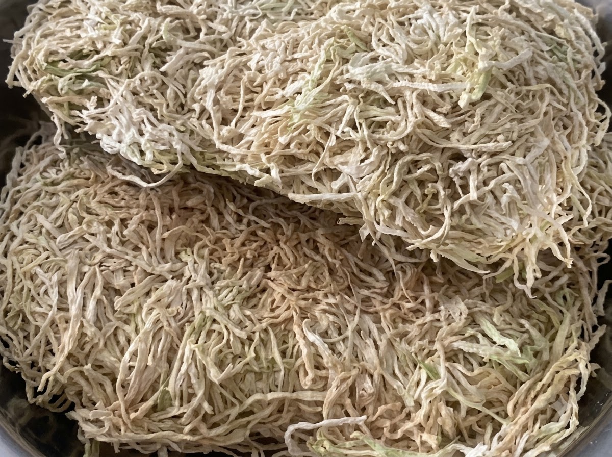 A close-up view of dried radish shreds piled inside a metal container.