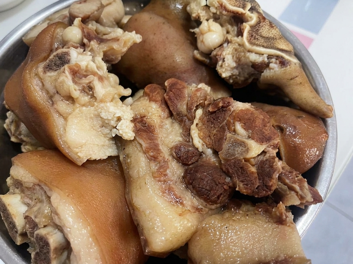 Cooked pork pieces resting in a bowl, ready to be cut into smaller chunks.