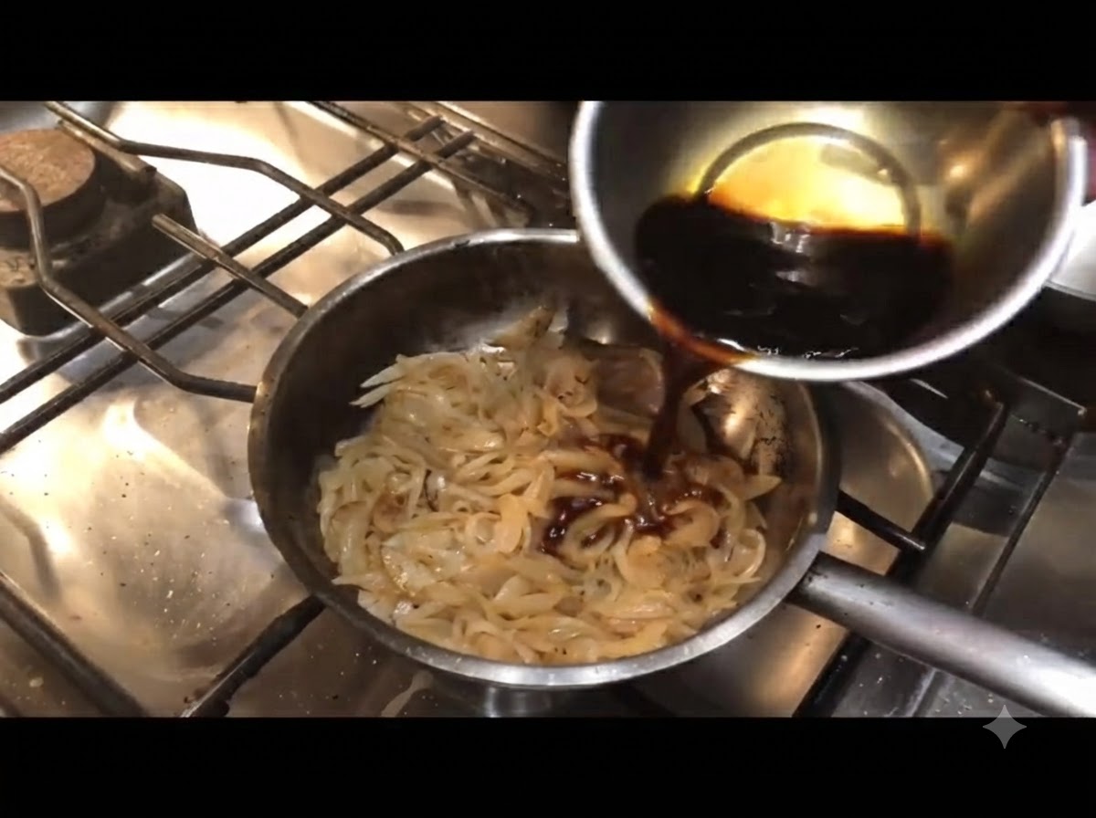 Dark sauce being poured from a small bowl into a pan of cooked onions.