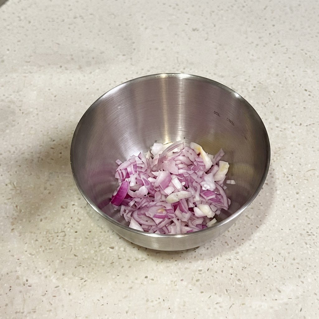 Finely chopped red shallots and scallions in a small metal bowl ready to be mixed with seasonings.