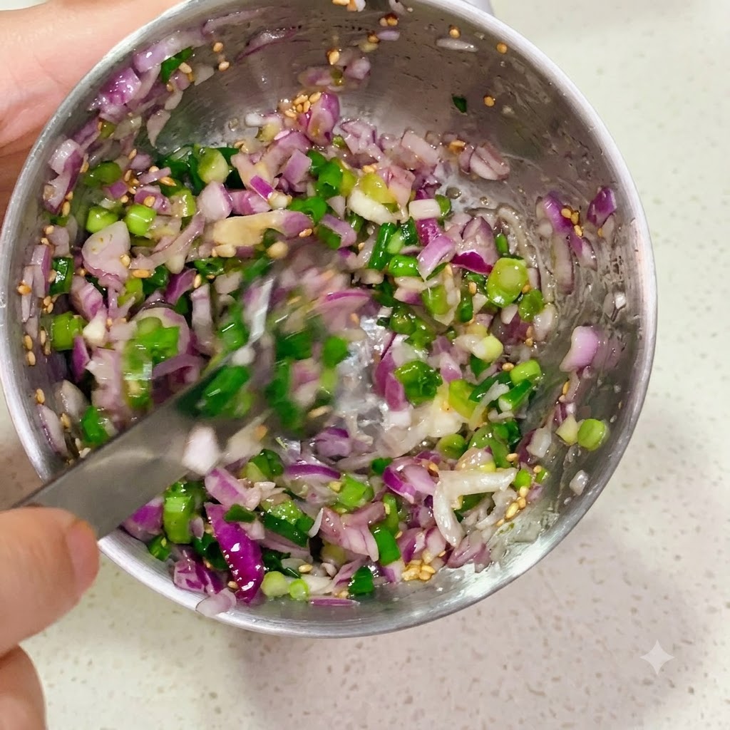 A metal bowl filled with finely chopped red and green onions being mixed with a spoon.