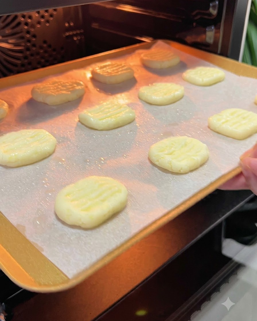 A baking tray with potato pancakes being slid into the glowing interior of a preheated oven.