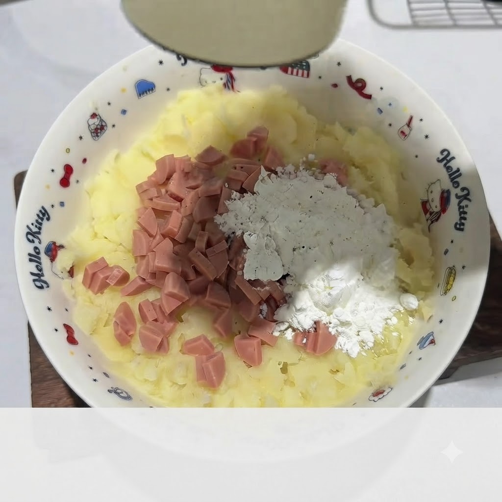 Gloved hand kneading the mashed potato mixture with ham and starch into a dough inside the white bowl.