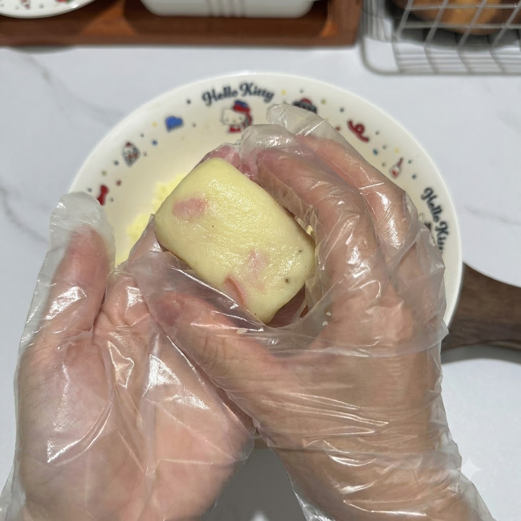 Gloved hands shaping a piece of potato dough into a neat rectangular patty.