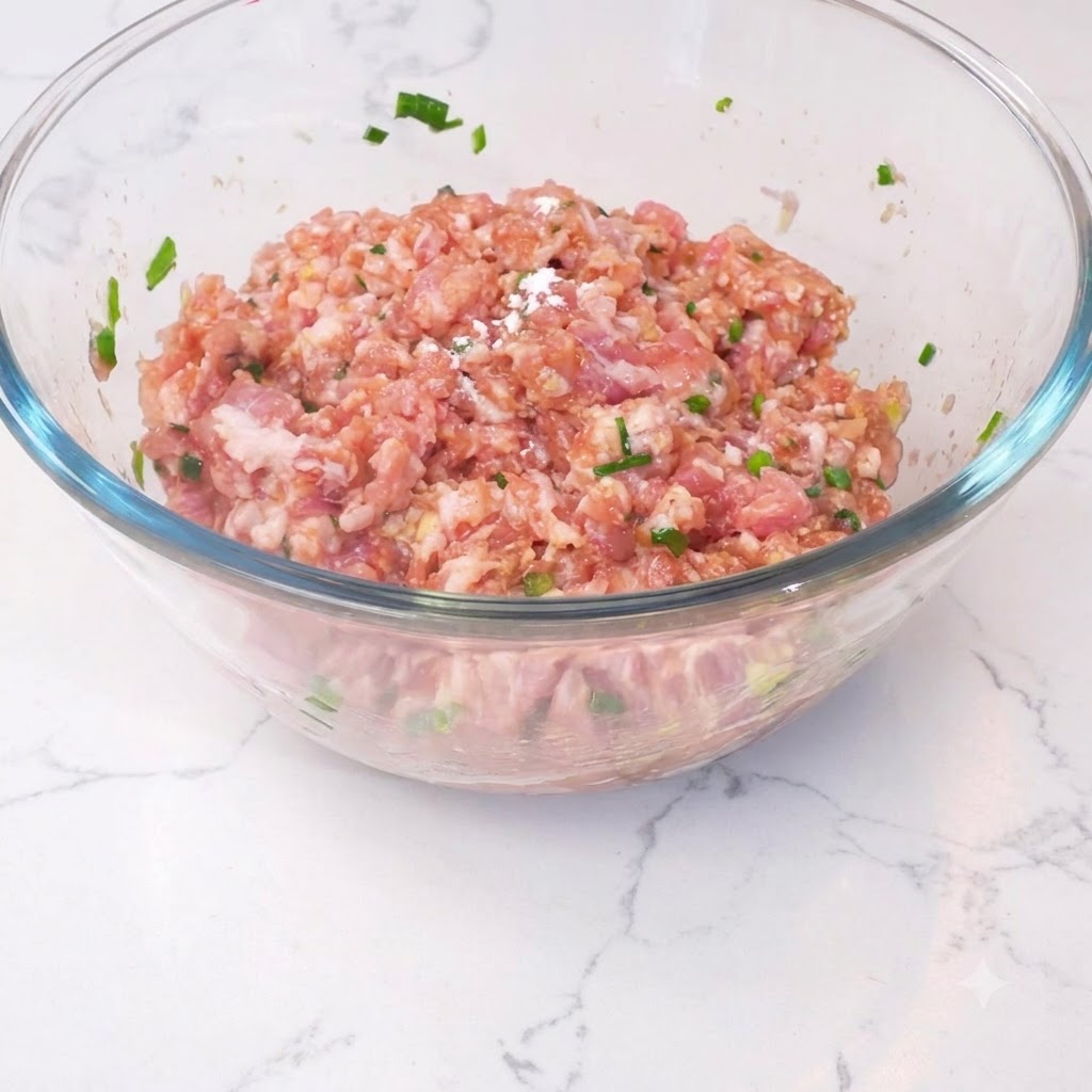 Cornstarch sprinkled over the meat mixture in a glass bowl.
