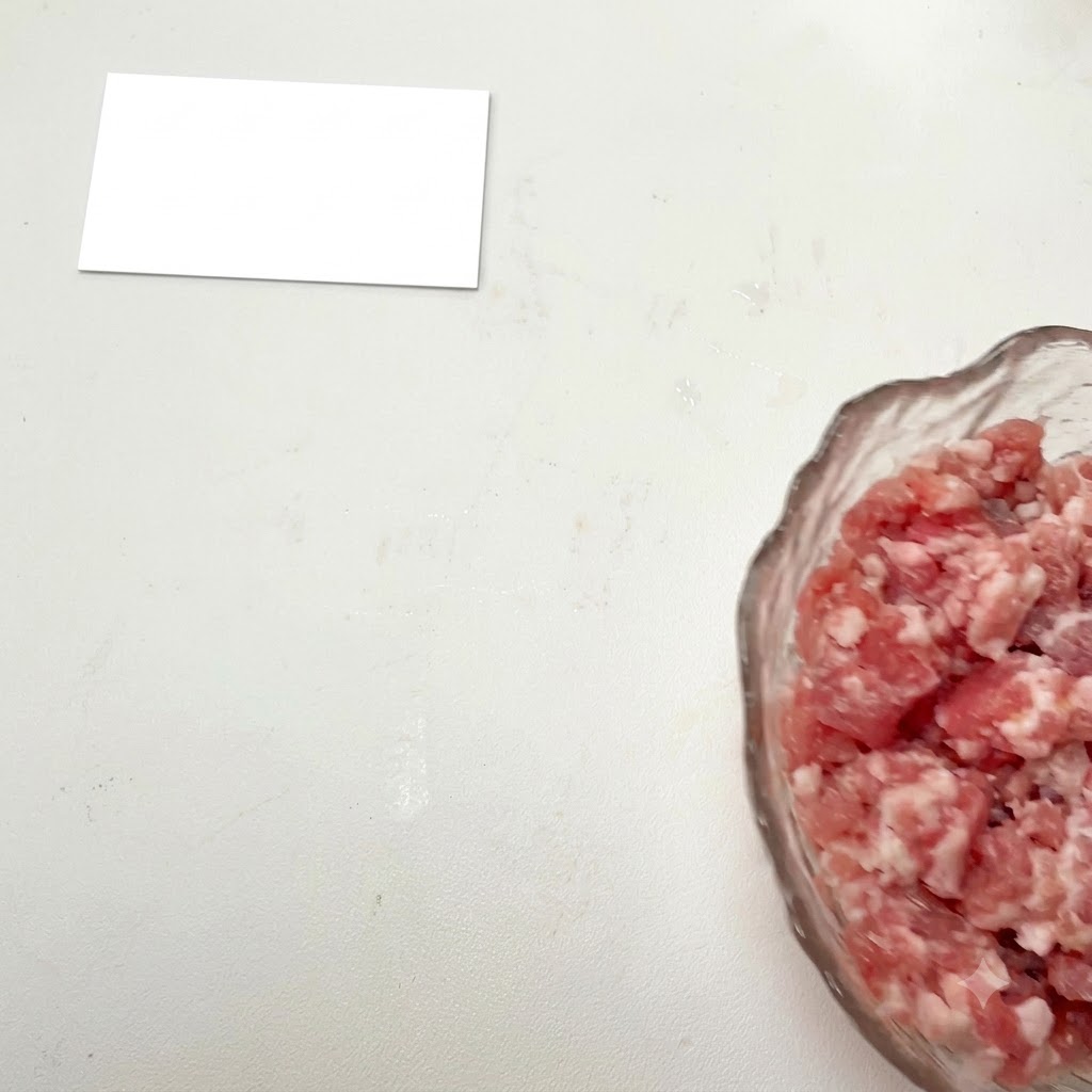 Minced meat in a glass bowl with seasonings being added.