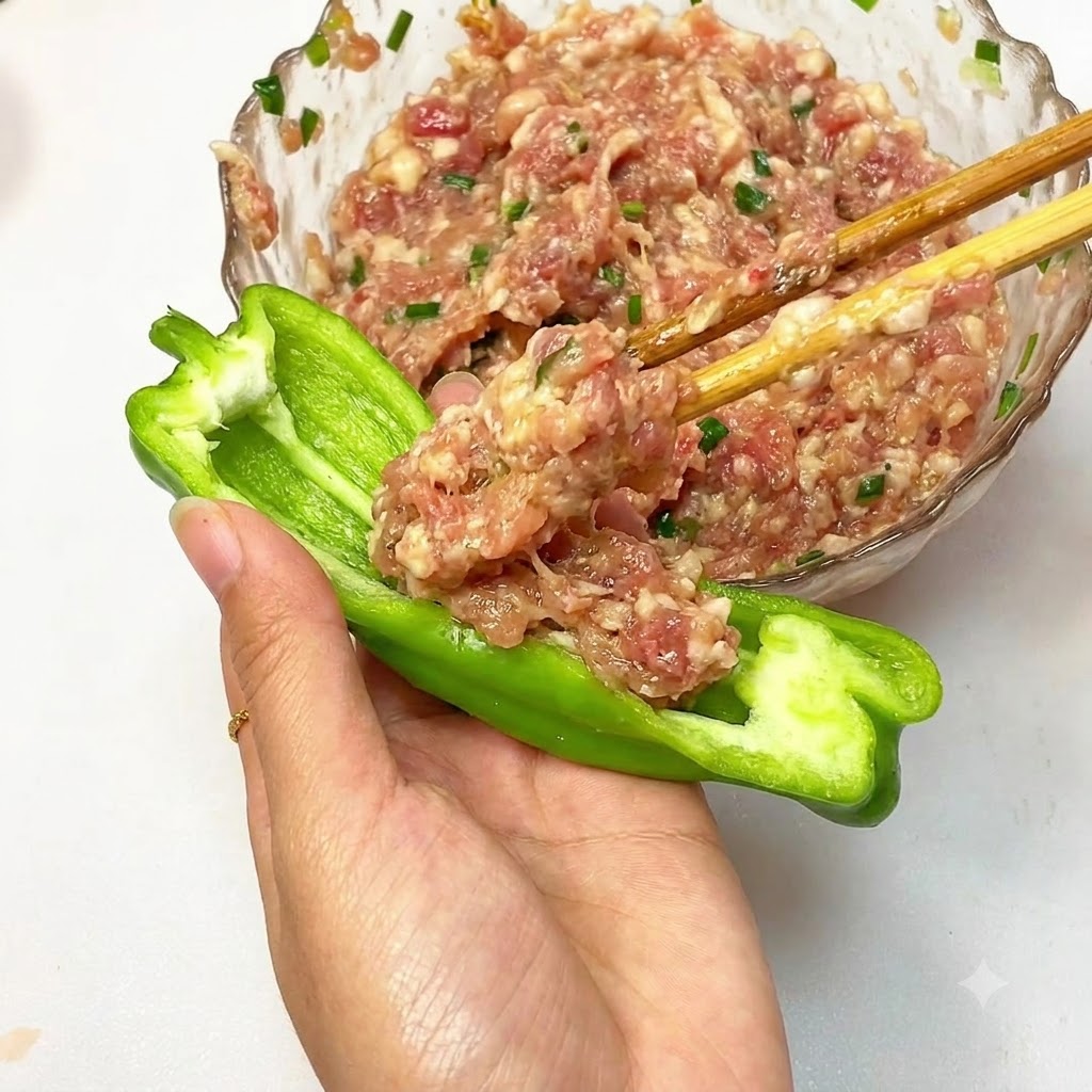 Minced meat filling being stuffed into a halved green pepper.