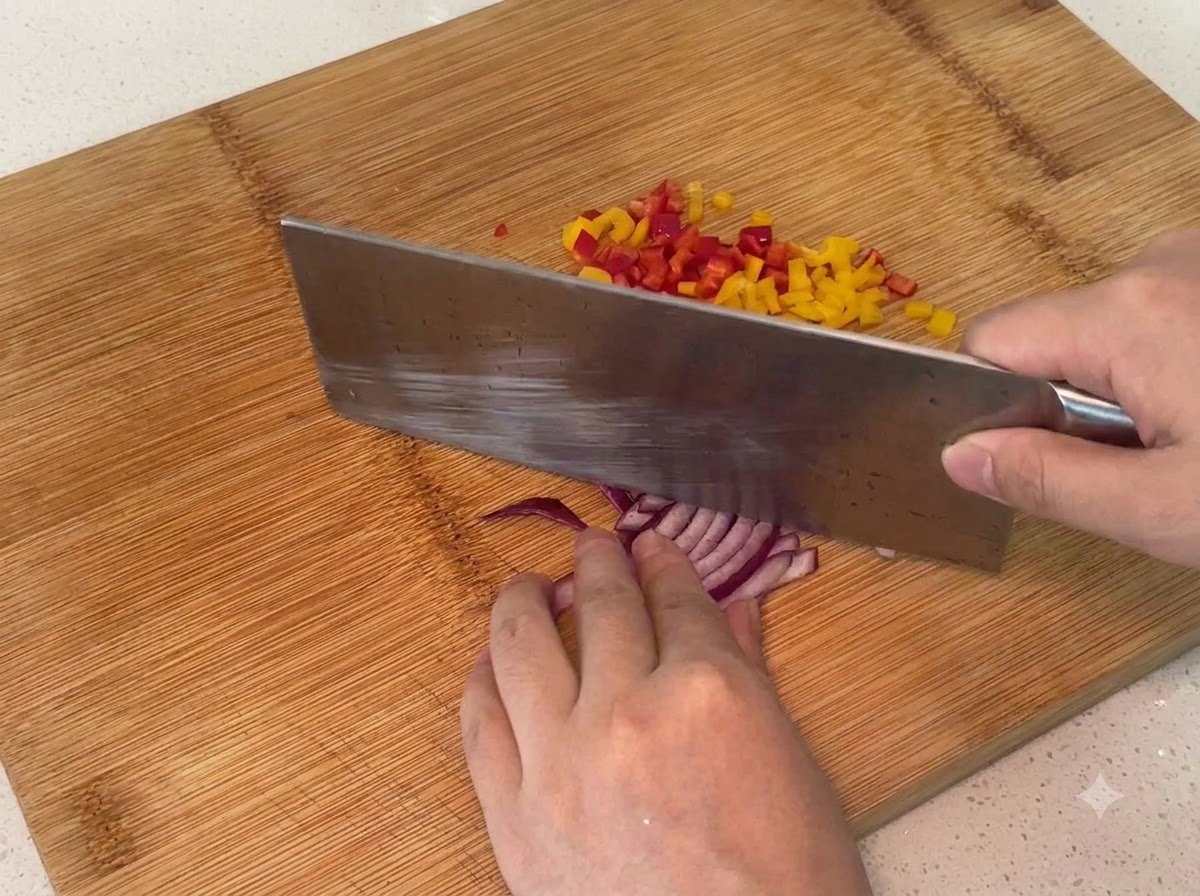 Red onion being chopped into small pieces on a wooden cutting board.