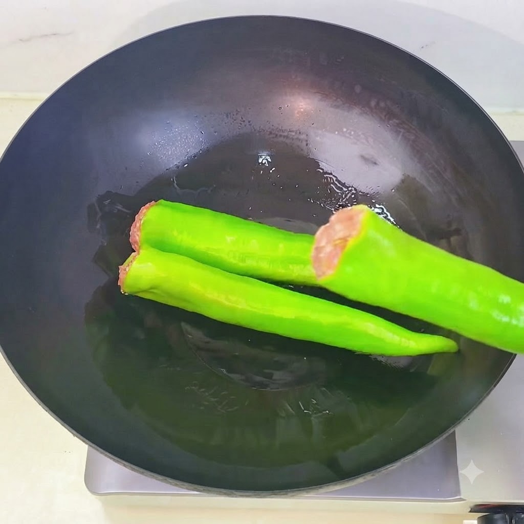 Stuffed green peppers being arranged in sequence inside a heated wok with oil.