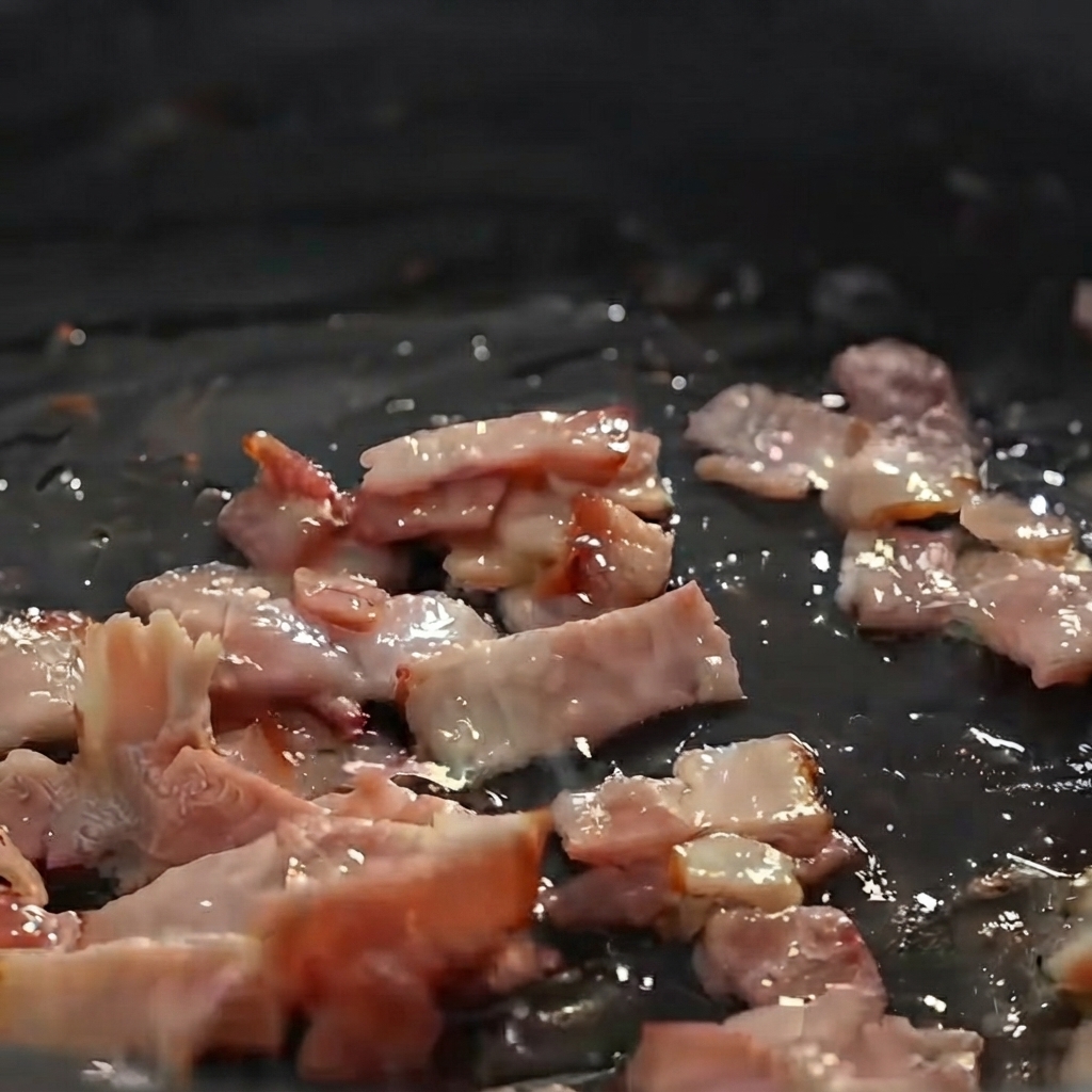 Diced potatoes, onions, and celery being sautéed with bacon pieces in a frying pan.