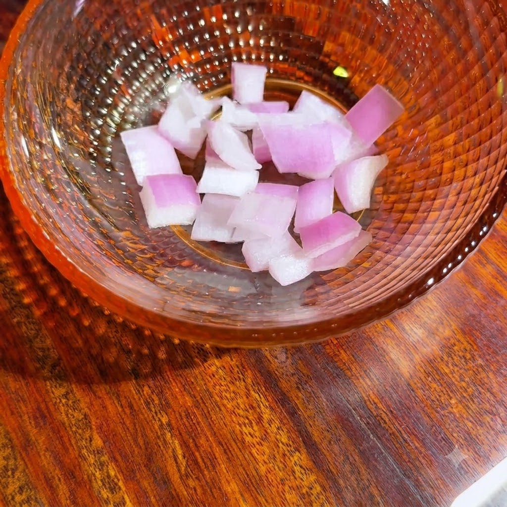 A glass bowl containing freshly diced red onion pieces ready for the avocado salsa.