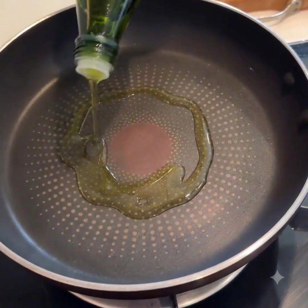 Bacon sizzling in a frying pan with olive oil coating the bottom.