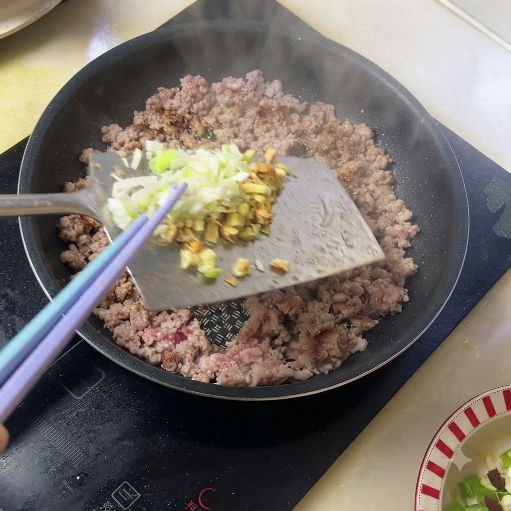 Chopped green onions and ginger being added to cooked minced pork in a pan.