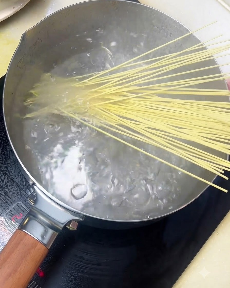 Alkaline noodles being added into a pot of boiling water.