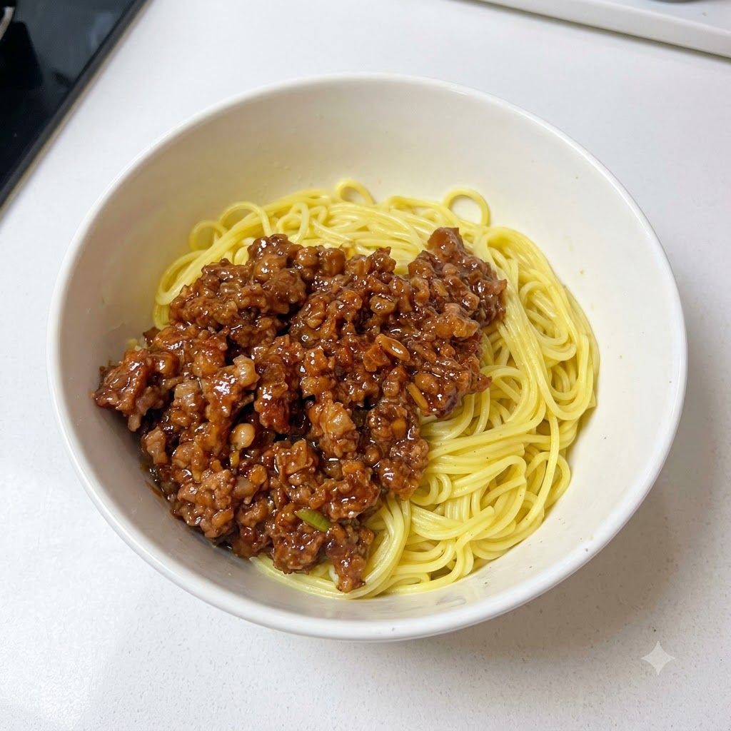 A bowl containing noodles and minced meat sauce topped with freshly chopped green onions.