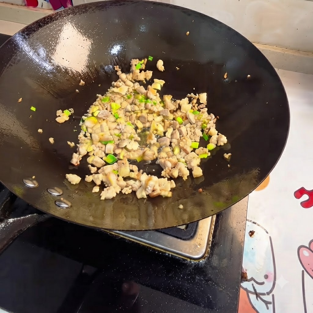 Minced meat and aromatics being stir-fried in a wok.