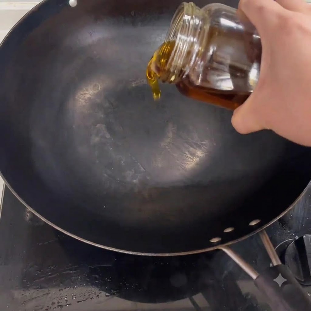 Cooking oil pouring from a jar into a black wok placed on a stove.