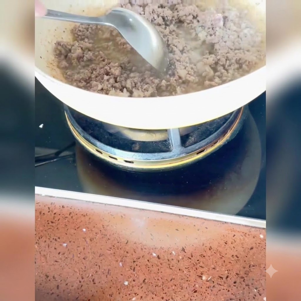 Minced scallions, ginger, and garlic being stirred into the cooked meat in the pan.