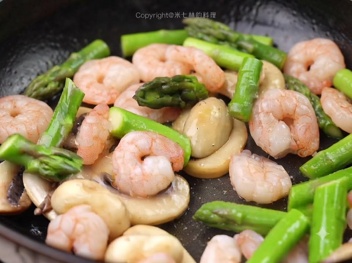 Blanched shrimp and green asparagus pieces being added into the pan with the mushrooms.