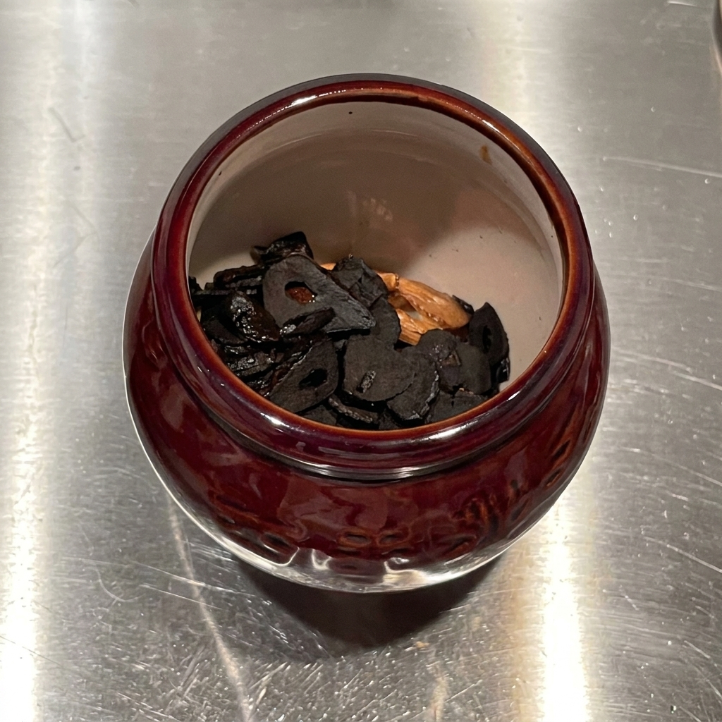 Garlic-infused oil being poured from above into a ceramic mortar filled with fried garlic chips.