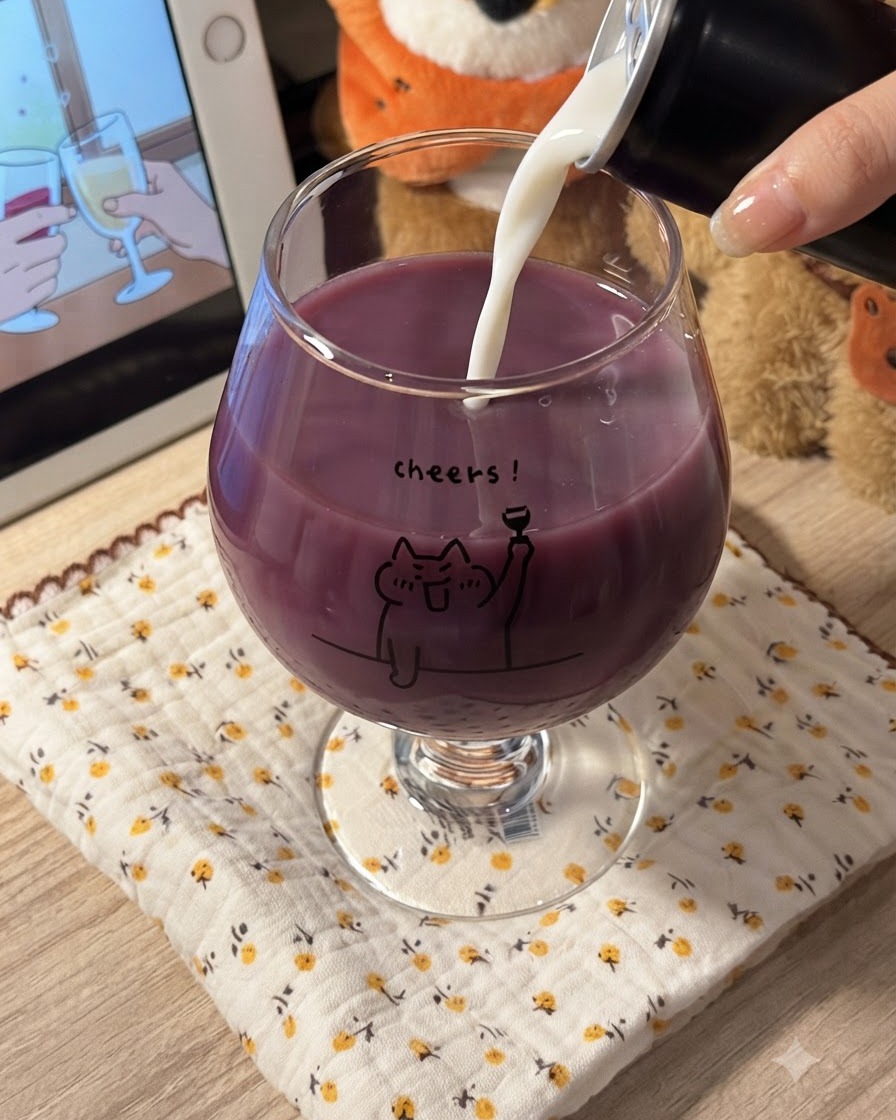 White milk being poured into a glass filled with purple grape juice, creating a creamy purple blend.