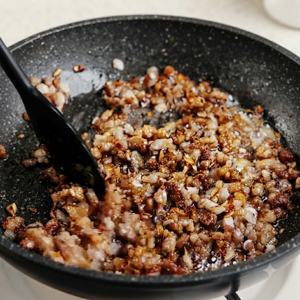 Chopped green chive and scallion stems being mixed into a simmering pan of seasoned minced meat.