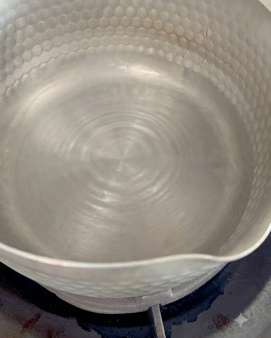 Dried bonito flakes boiling in a small pot with simmering water to create a flavorful dashi stock.