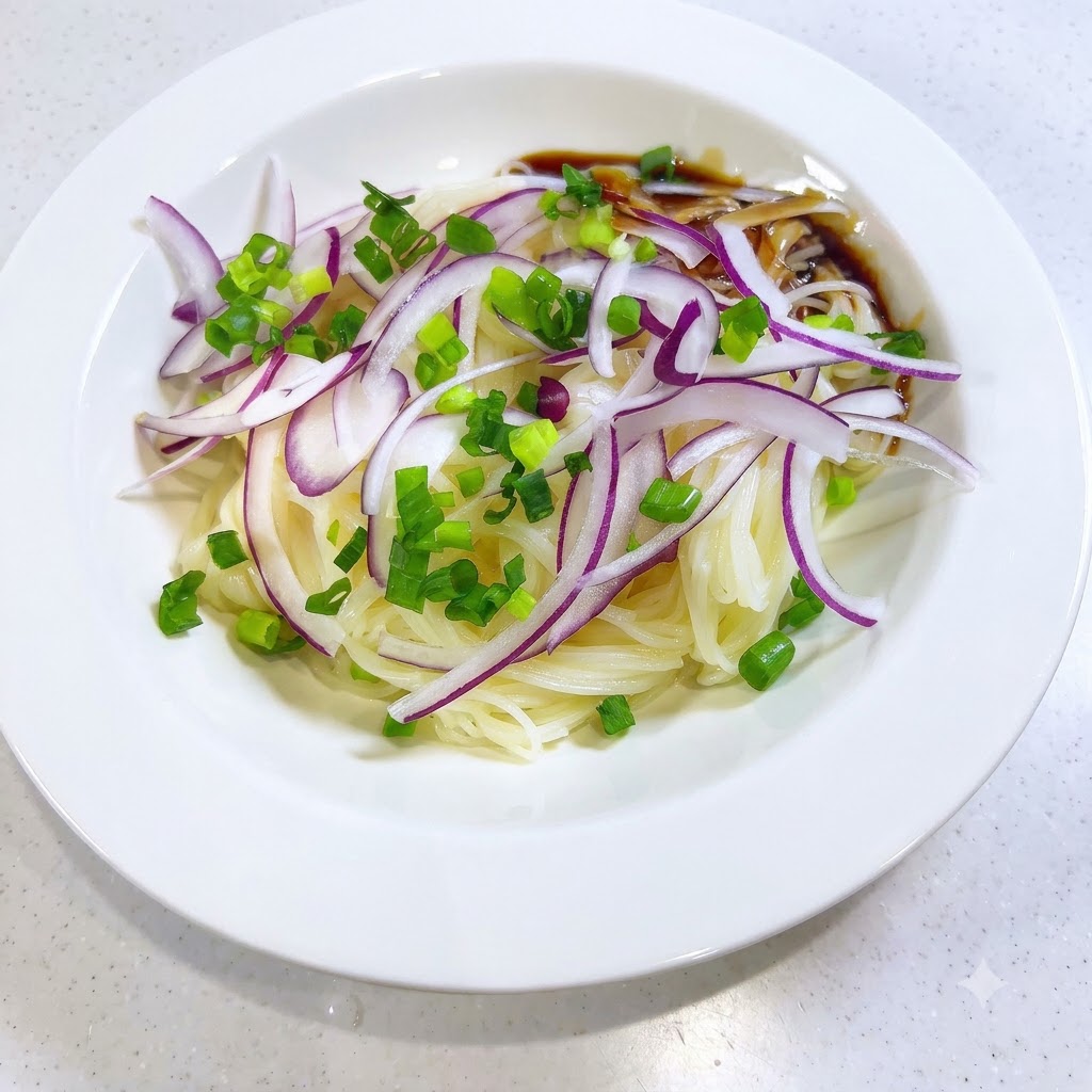 Dark savory sauce being poured onto the side of the somen noodles and onion toppings in a white bowl.